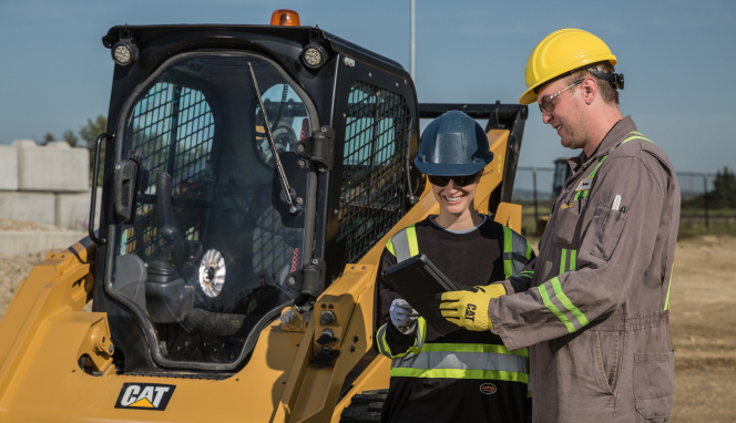 2 people standing next to heavy machinery