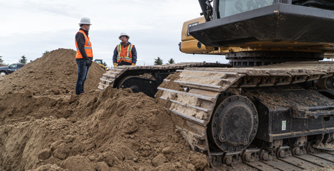 Heavy machinery on a work site, with 2 men in the backround