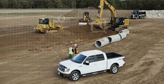 worksite with heavy machinery , 2 people working and a pick-up truck