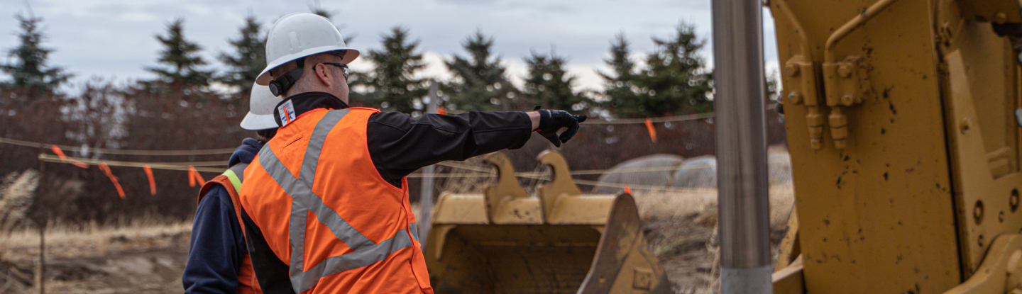 Heavy machinery on a work site, with 2 men in the backround